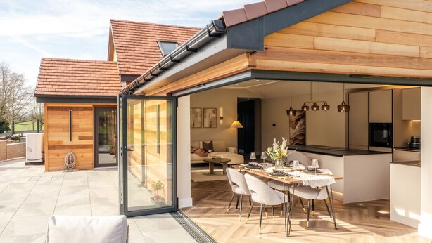 Ein modernes Haus mit einem verglasten Essbereich, einer Küche und einem Wohnzimmer.