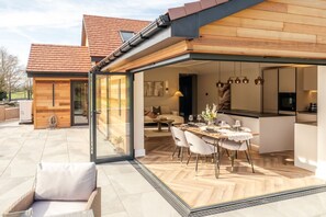 Une maison moderne dotée d’un espace repas entièrement vitré, d’une cuisine et d’un salon.