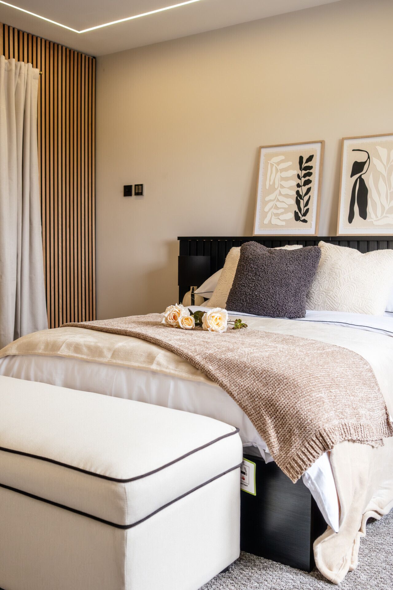 A neatly arranged bedroom with a bed, bedside tables, and a large window with curtains.