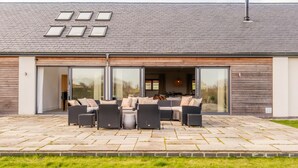 A modern house with a patio, large windows, and a chimney.