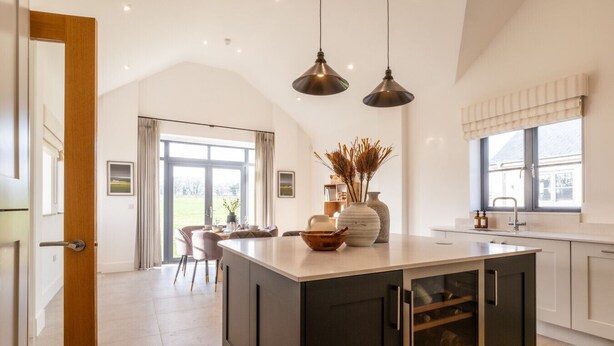 A modern kitchen with a central island, pendant lighting, and a view to the outdoors.