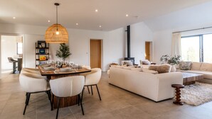 A modern living room with a dining area, a sofa set, and a fireplace.