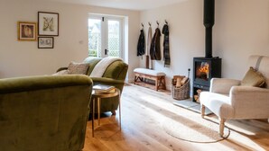 Ein gemütliches Wohnzimmer mit Kamin, grünen und beigen Sofas, einer Bank und Holzboden.
