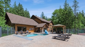 Eine Lodge mit Poolbereich, Sitzgelegenheiten im Freien und einer überdachten Terrasse.