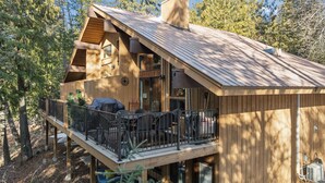 Eine Holzhütte mit Balkon, Grill und Sitzgelegenheit im Freien.