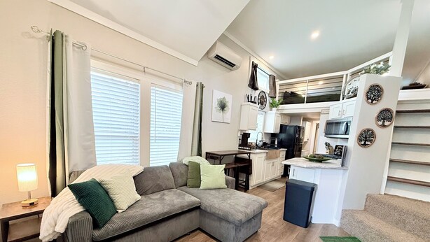 Una sala de estar moderna con un sofá seccional, un comedor, una cocina y una escalera.