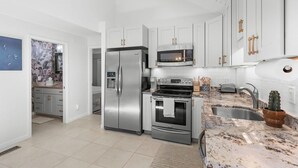 A modern kitchen with stainless steel appliances, white cabinetry, and a granite countertop. - Fabulous 2 bed with a loft! Amenities included! Pets NOT allowed (Seabrook Island)