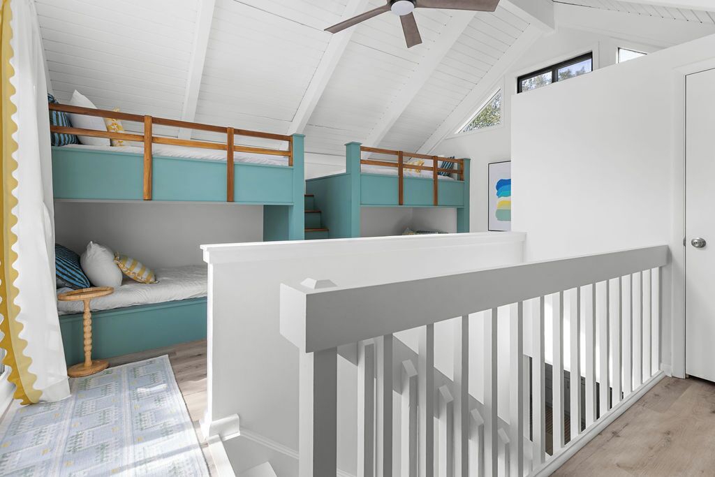 Ein Zimmer mit einem Etagenbett, einem Deckenventilator und einer Treppe.