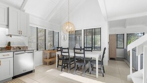 A modern kitchen with white cabinetry, a dining area with a white table and chairs, and a staircase leading to another level. - Fabulous 2 bed with a loft! Amenities included! Pets NOT allowed (Seabrook Island)