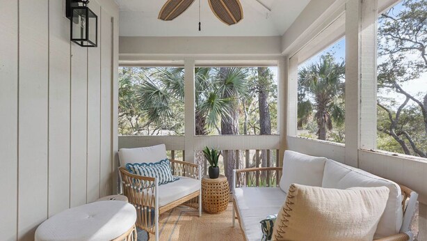 A room with a white wicker sofa, a small round table, and a potted plant. - Fabulous 2 bed with a loft! Amenities included! Pets NOT allowed (Seabrook Island)
