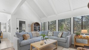A spacious living room with a high ceiling, a grey sofa, a wooden coffee table, and large windows. - Fabulous 2 bed with a loft! Amenities included! Pets NOT allowed (Seabrook Island)