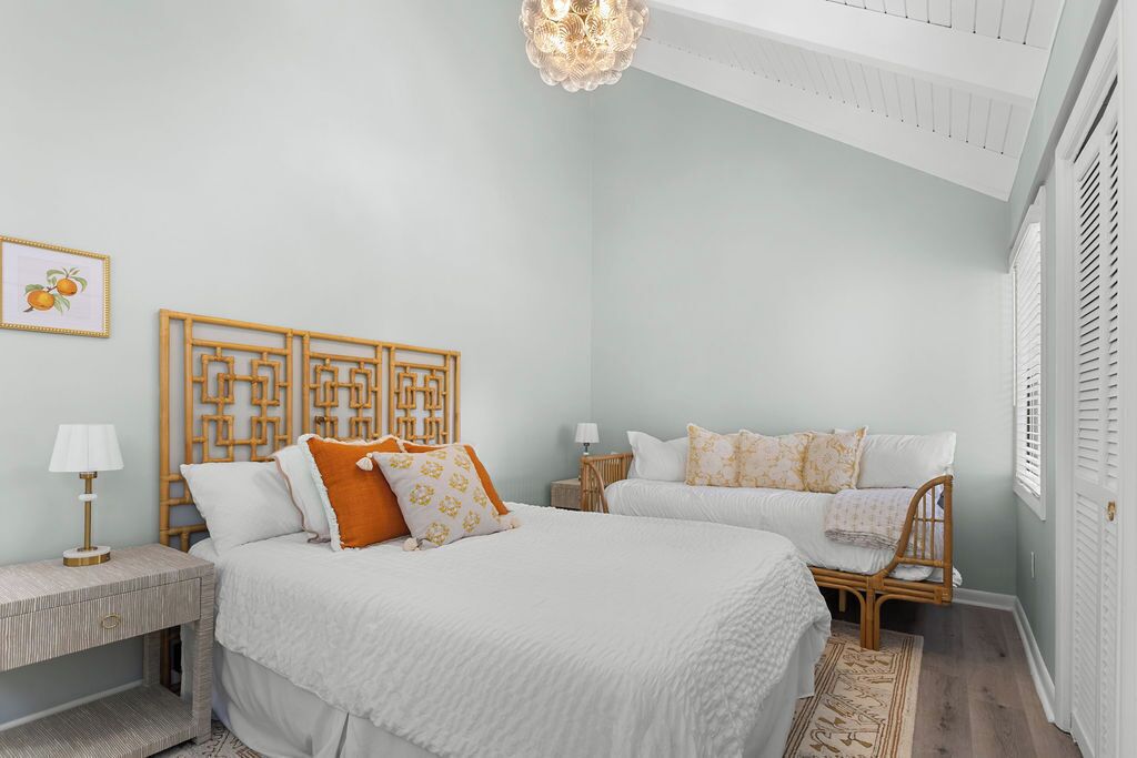 Une chambre à coucher avec un grand lit, deux tables de chevet, un luminaire fixé au mur et une fenêtre avec des volets.