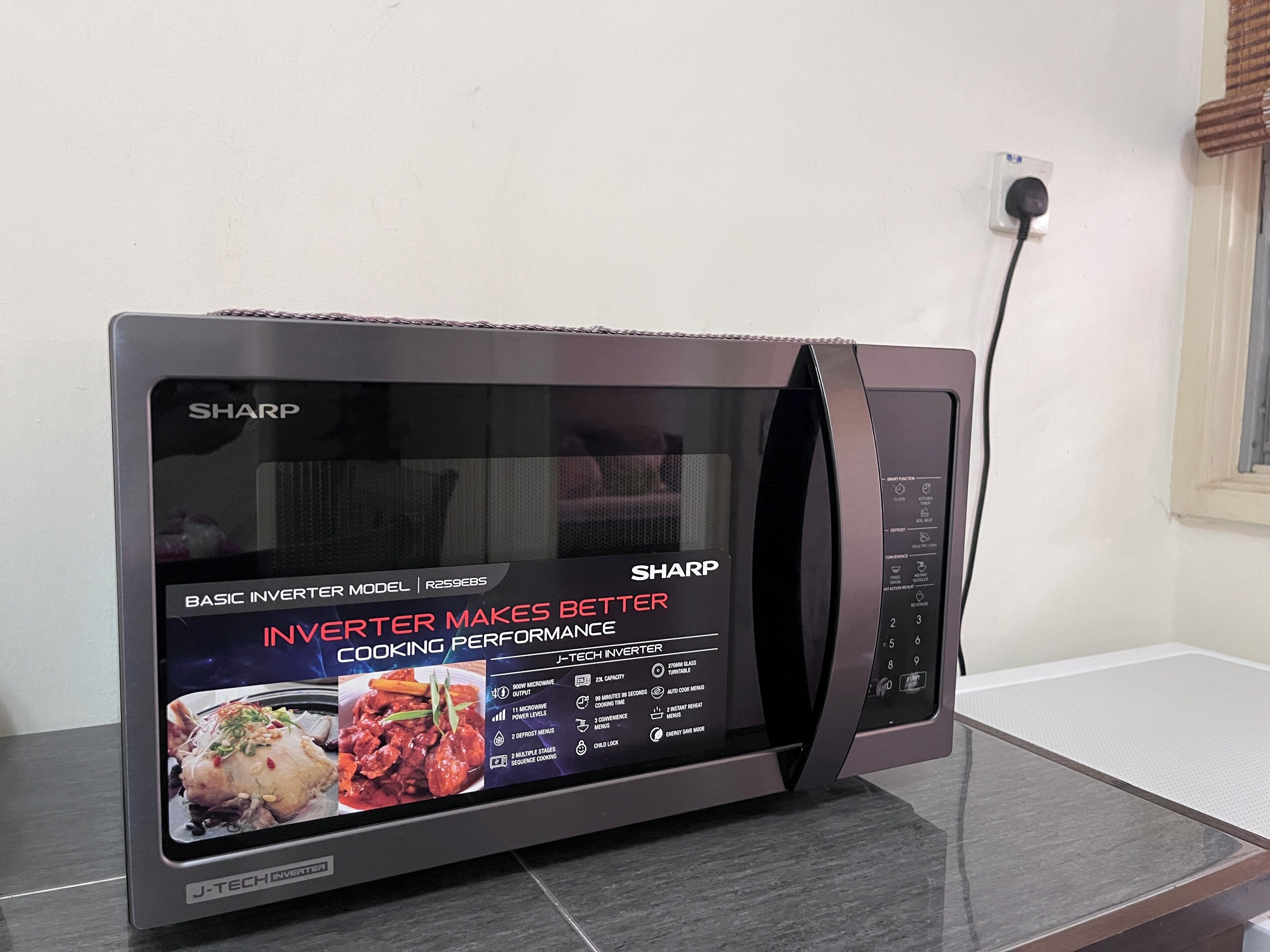 En Sharp mikrobølgeovn med digitalt display, knapper til betjening og børnesikring.