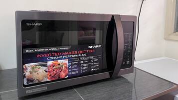 En Sharp mikrobølgeovn med digitalt display, knapper til betjening og børnesikring.