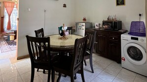 Un coin repas avec une table ronde, des chaises, un lave-linge et des appareils de cuisine.