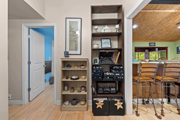 A room with a wooden floor, a bookshelf with various items, a bar area with stools, and a sign that reads 'Welcome to Lake House.' - Lakefront Home on Old Hickory Lake (Old Hickory)