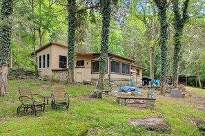 A rustic cabin surrounded by trees, with outdoor seating and a fire pit. - Lakefront Home on Old Hickory Lake (Old Hickory)