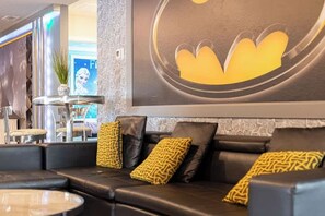 A modern lounge area with a black leather sofa, a round table, and a decorative wall with a circular design. - Luxury 9BR Windsor Island Pool Game Room (Davenport)