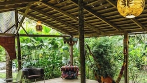 Une terrasse en bois avec un hamac, des chaises et une table.
