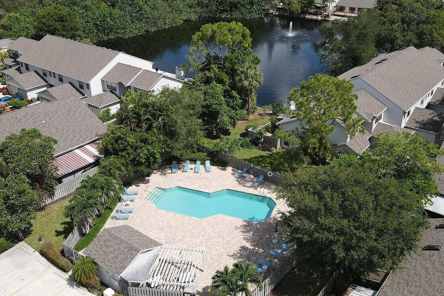 Uma área residencial com piscina, cercada por espreguiçadeiras e um deck com grade.