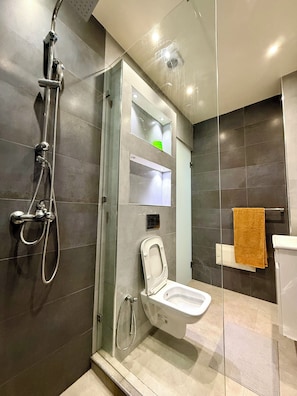 A modern bathroom with a glass-enclosed shower, a toilet, and a towel rack.