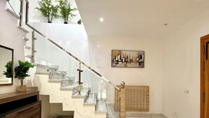Ein modernes Interieur mit einer Marmortreppe, einem Holzschrank und einem gerahmten Kunstwerk an der Wand.