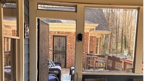 A covered patio area with outdoor furniture, a brick wall, and a wooden door. - FIFA READY! Spacious 8-bedroom Retreat in Stone Mountain (stone mountain)