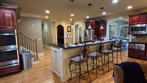 A spacious kitchen with a central island, wooden flooring, and built-in appliances. - FIFA READY! Spacious 8-bedroom Retreat in Stone Mountain (stone mountain)
