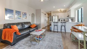 A modern living room with a black leather sofa, a white coffee table, and a kitchen in the background. - Jamaica Bay 308B (Ocean City)