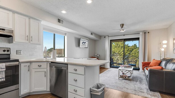 A modern kitchen with white cabinets, a built-in oven, and a large island with drawers. - Jamaica Bay 308B (Ocean City)