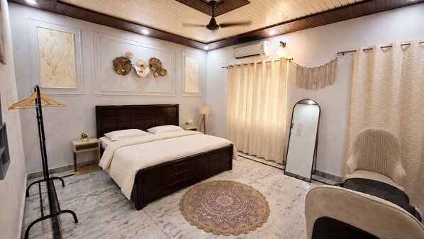 Un dormitorio con cama, mesitas de noche, una lámpara de pie, una silla, un espejo y una alfombra estampada.