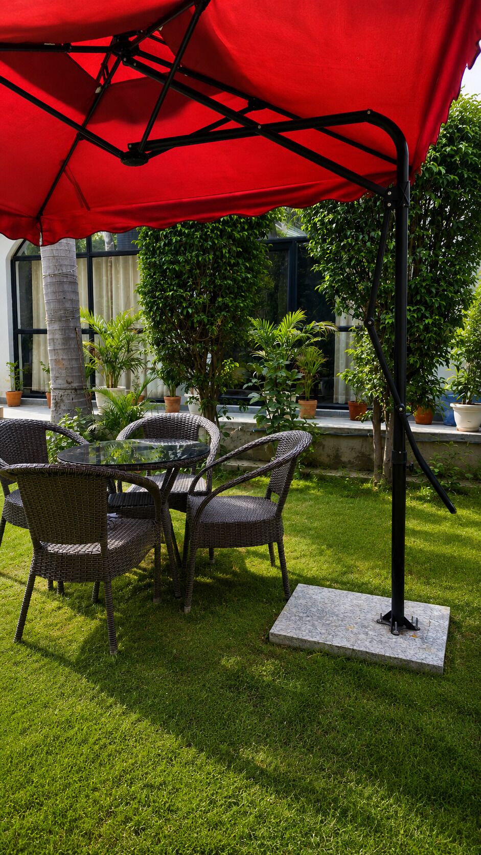 Une terrasse extérieure avec des meubles en osier et un parasol rouge.