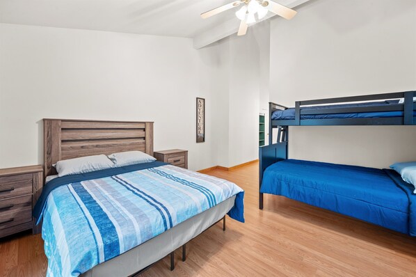 Une chambre à coucher avec un lit en bois, un lit superposé, une table de chevet et un ventilateur de plafond.