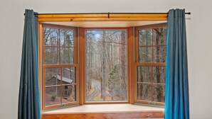Ein Zimmer mit einem großen Erkerfenster mit Blick auf ein bewaldetes Gebiet.