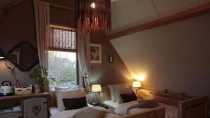 A cozy, rustic bedroom with two wooden beds, a desk with a mirror, and a window with curtains. - B&B De Zwerver (Oldehove)