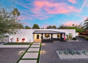 Ein modernes Haus mit Terrasse, Flagge und Garten.