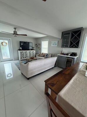 A modern living room with a sofa, a wooden coffee table, a TV, and a cabinet. - Canal front 4-bedroom house in Blackwater Sound, Key Largo near Adams Cut (Key Largo)
