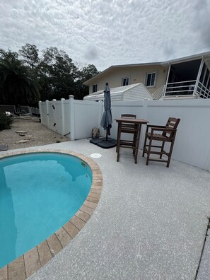 A backyard with a swimming pool, a patio table, and two chairs. - Canal front 4-bedroom house in Blackwater Sound, Key Largo near Adams Cut (Key Largo)