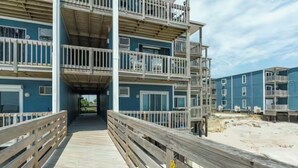 Ein mehrstöckiges Gebäude mit Balkonen, einer Holzterrasse und Blick auf den Strand.