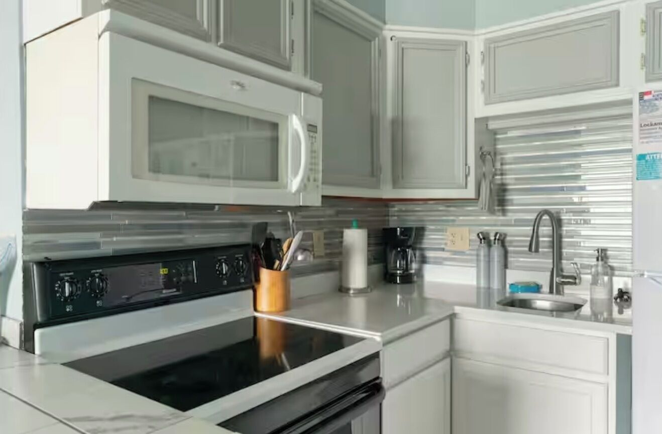 A kitchen with a microwave, stove, sink, and cabinets.