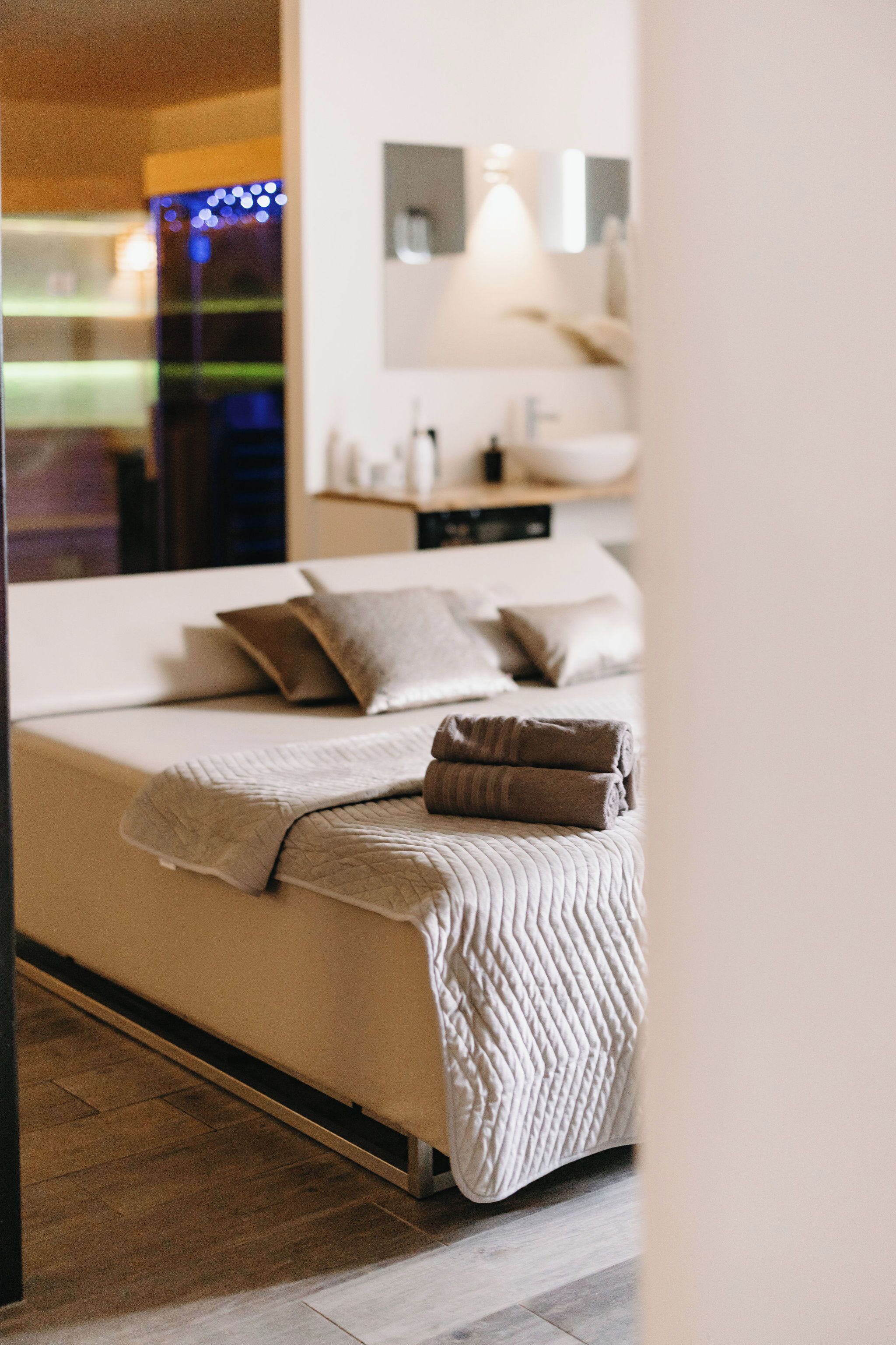 Un dormitorio con cama, almohadas, mesita de noche y espejo.