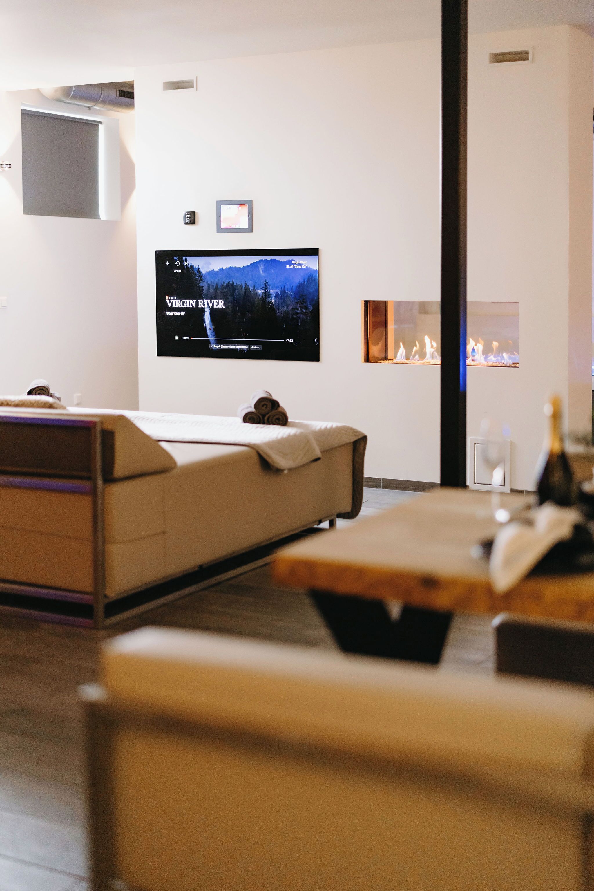 Una habitación moderna con una televisión de pantalla plana, chimenea, sofá y una mesa de madera.