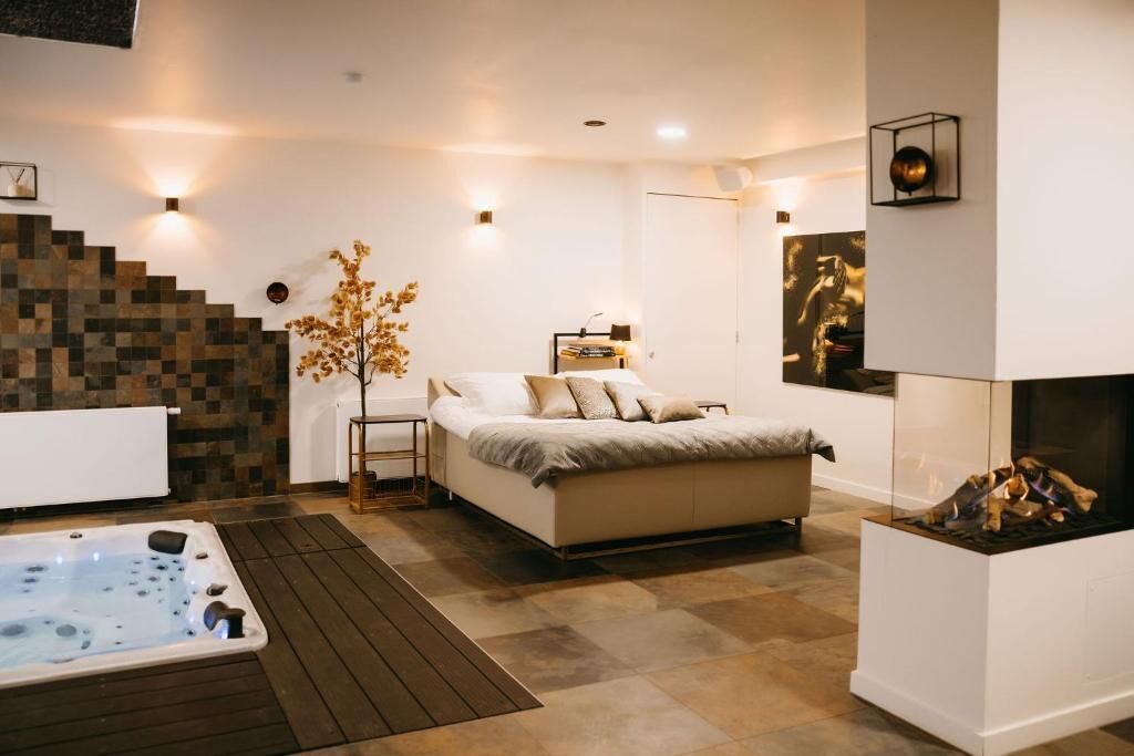 Une chambre moderne avec un grand lit, un jacuzzi et une cheminée.