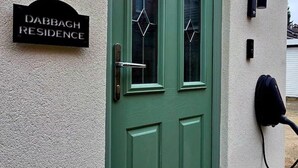 Une porte verte avec une plaque indiquant « Résidence Dabbagh » et deux lampes fixées au mur.