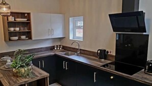 Une cuisine moderne avec une table à manger en bois, des placards intégrés, une cuisinière noire et une fenêtre.