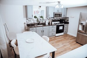 A modern kitchen with white cabinets, a marble countertop, and stainless steel appliances. - Two Bedroom Home, 10min Downtown Boston, Logan Airport and Free Parking (Revere)