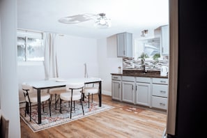 Een moderne keuken met witte kasten, een houten aanrechtblad en een eethoek met een tafel en stoelen.