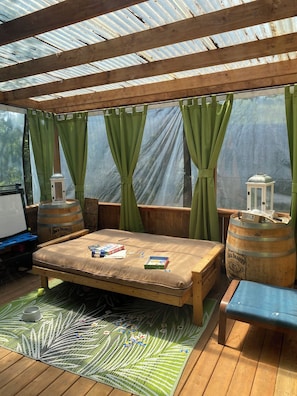 Un espace extérieur abrité, aménagé avec un banc en bois, une table et un tapis vert.