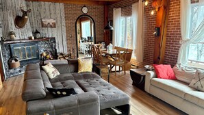 A cozy living room with a sectional sofa, a dining area, and a fireplace. - The Hidden Gem (Gracefield)