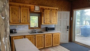 A wooden cabin kitchen with a microwave, toaster, and sink. - The Hidden Gem (Gracefield)